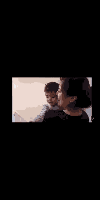 a woman is holding a baby in her arms while looking at herself in the mirror .