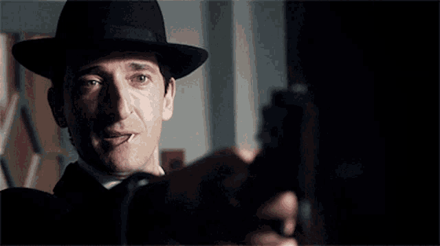 a man in a hat is pointing a gun at someone