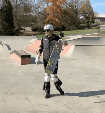 a person wearing a helmet and sunglasses holds a skateboard in their hand