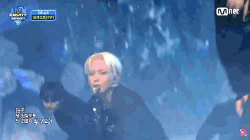 a group of people are performing in front of a mnet banner