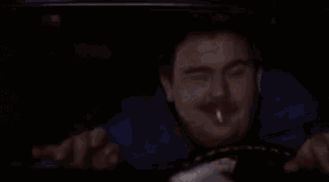 a man with a mustache is smoking a cigarette in a car .