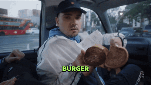 a man sitting in a car holding a hamburger with the word burger above him