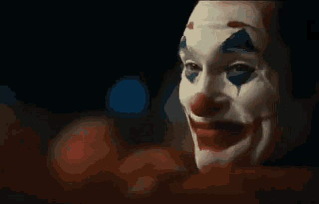 a close up of a person wearing a clown mask with blood on their face .