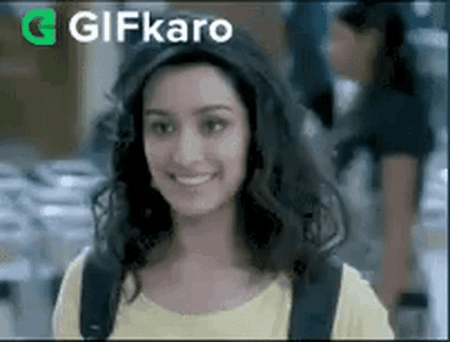 a woman wearing a yellow shirt and a backpack is smiling and looking at the camera .