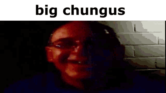 a man wearing glasses is smiling in a dark room with the words `` big chungus '' written above him .