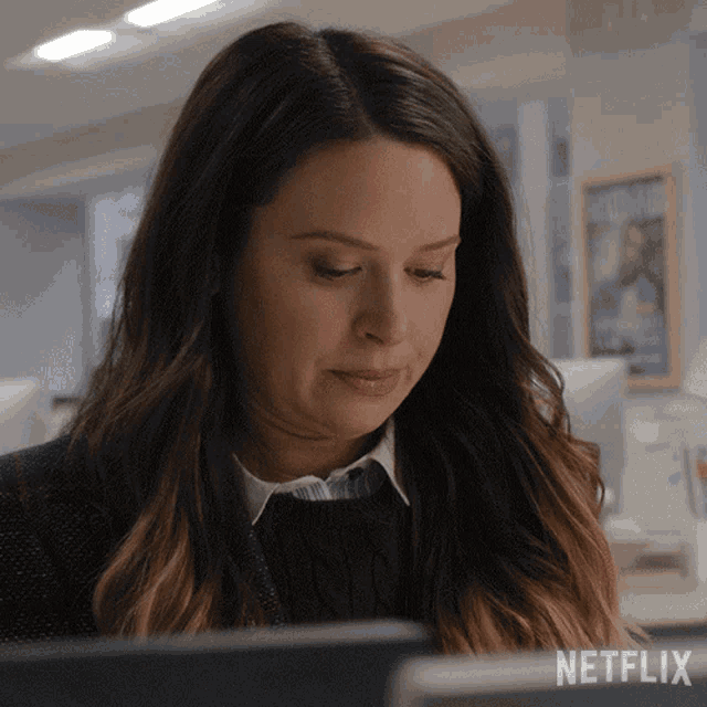 a woman sitting at a desk with a netflix logo on the bottom