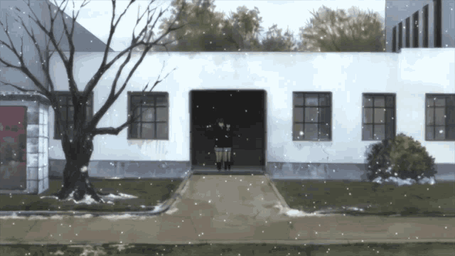 a person standing in front of a building with snow falling on the ground