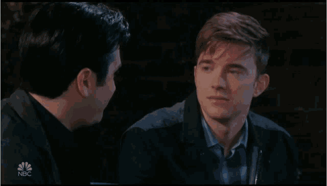 two men are talking in front of a brick wall with nbc written on the bottom