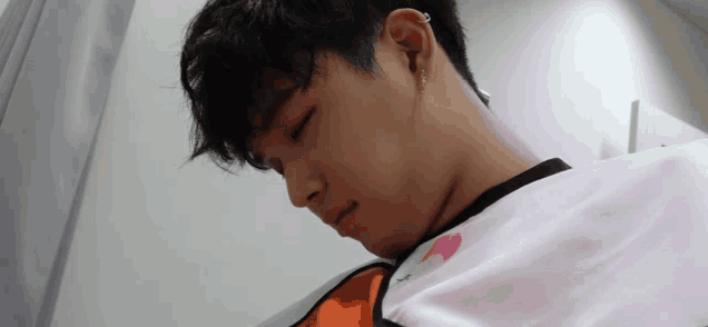 a close up of a person 's face with their eyes closed and a white shirt with a pink heart on it