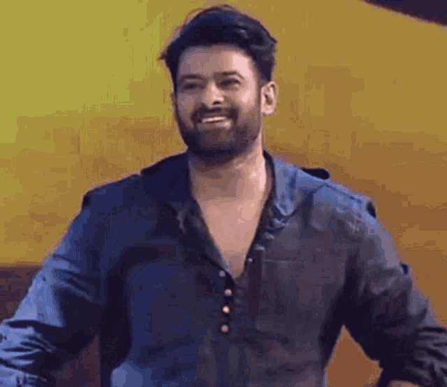 a man with a beard and a blue shirt is smiling .