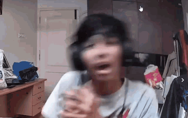 a person wearing headphones is making a funny face while sitting in front of a desk .