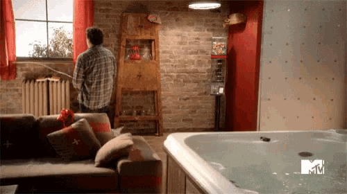 a man is standing in a living room next to a jacuzzi that says mtv on the wall