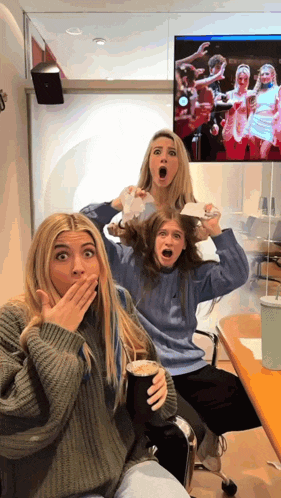 three girls are sitting in front of a large screen with a ballerina on it