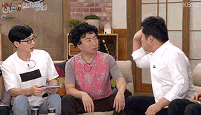 a group of people are sitting on a couch talking .