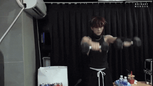 a man lifting a dumbbell in front of a curtain that says xdinary heroes