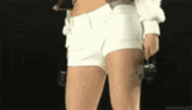 a woman in white shorts is holding a camera in her right hand .