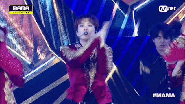 a man in a red jacket is dancing on a stage in front of a mnet sign