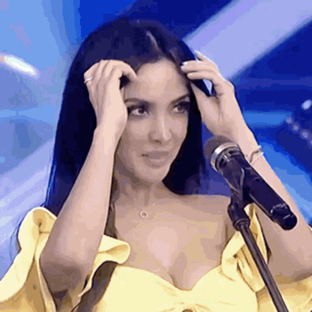 a woman in a yellow dress is standing in front of a microphone .