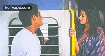 a man and a woman are standing next to each other on a bus .