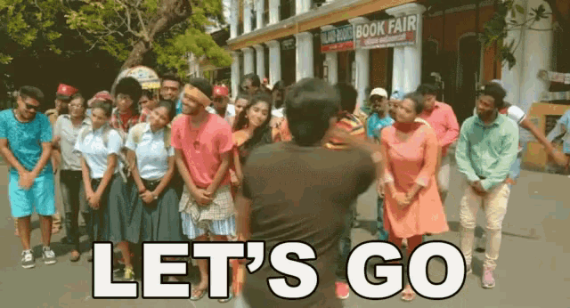 a group of people are dancing in front of a book fair sign