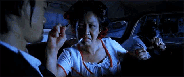 a woman is smoking a cigarette in a car while a man looks on .