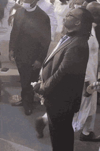 a man in a suit stands in front of a crowd of people