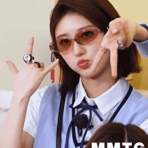 a woman wearing sunglasses and a watch is making a devil horns sign