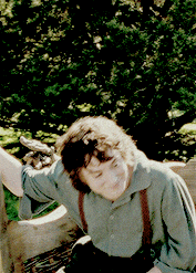 a man in a green shirt and brown suspenders is sitting on a bench