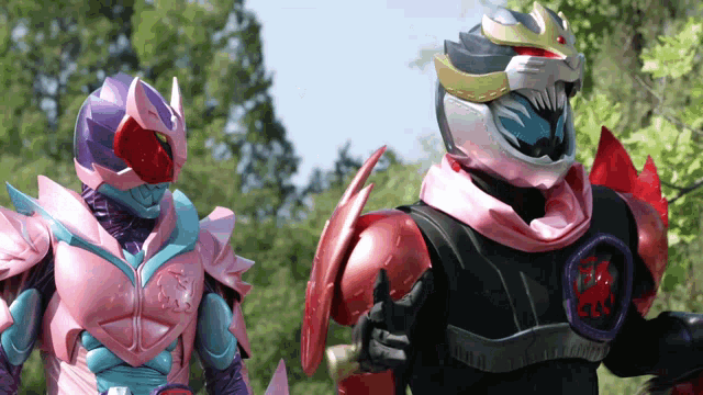 a man in a pink and purple costume is standing next to a man in a black and red costume