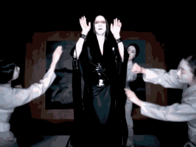 a woman in a black dress is surrounded by a group of people
