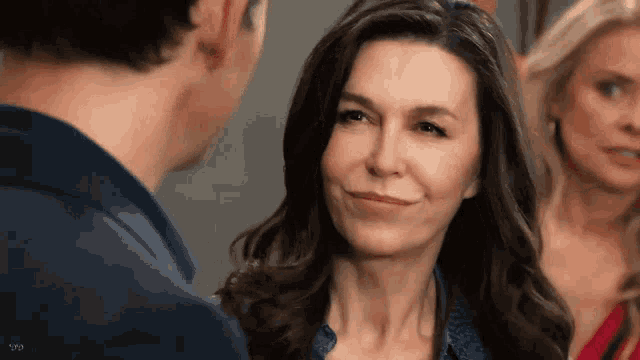 a woman is smiling while looking at a man in a blue shirt .