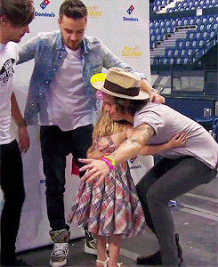 a man in a hat is hugging a little girl in front of a domino 's banner