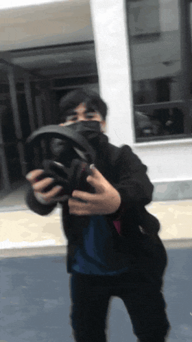 a man wearing a mask holds a pair of headphones