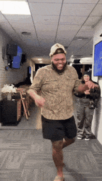 a man in a camo shirt is dancing in a room