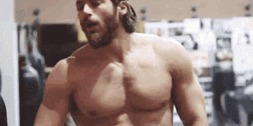 a shirtless man is standing in a gym .