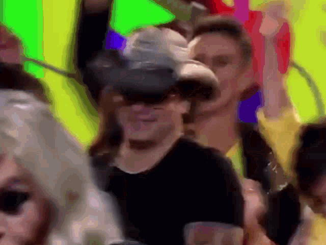 a woman wearing a cowboy hat and sunglasses is dancing in a crowd of people .