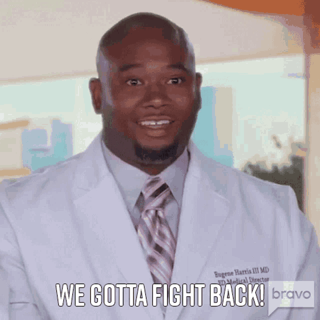 a man in a white coat and pink tie says we gotta fight back