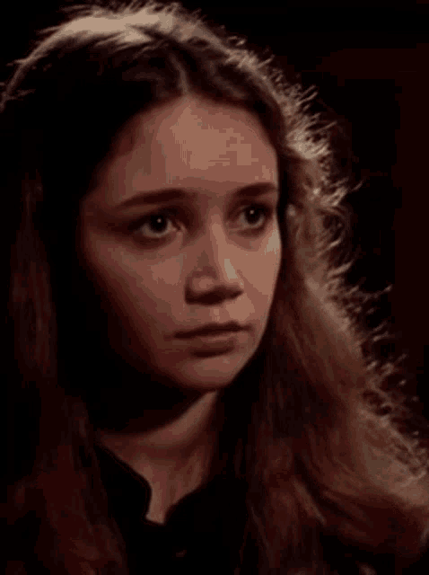a young girl with long brown hair looks at the camera