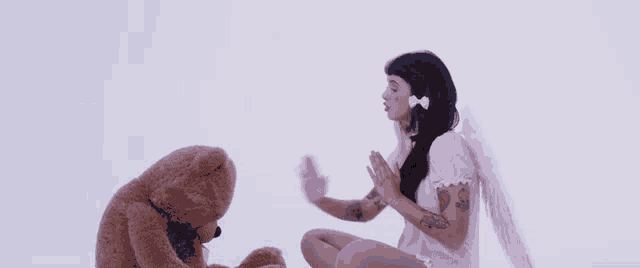 a woman in a pink dress with angel wings is sitting next to a teddy bear