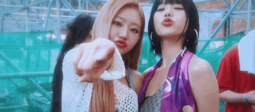 two young women are standing next to each other and pointing at the camera .