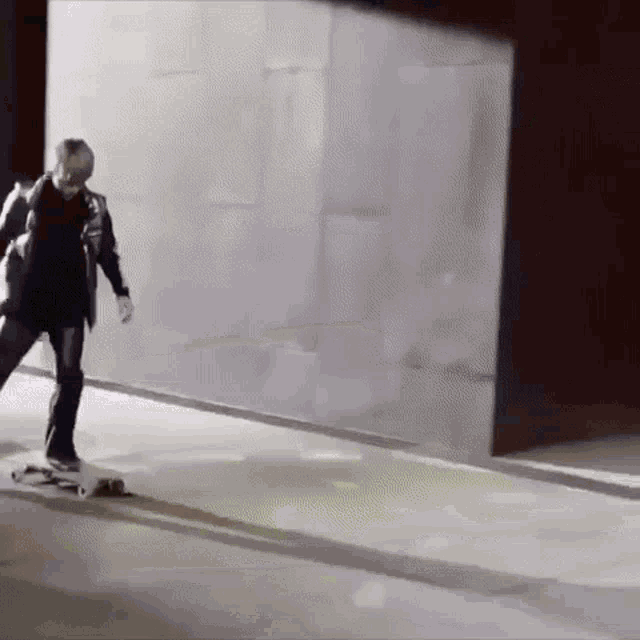 a person is riding a skateboard down a street in front of a wall .