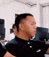 a man in a black shirt is standing in front of a computer screen in a room .