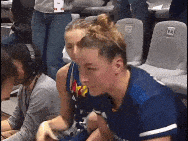 a woman in a blue jersey with the number 8 on it sits next to a man wearing headphones