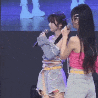 two girls are standing next to each other holding microphones .