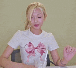 a woman in a white shirt with a pink bow on it is clapping
