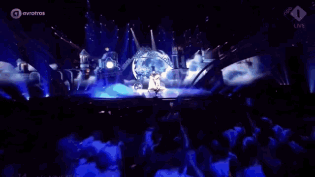 a woman in a white dress is standing on a stage in front of a giant snow globe ..