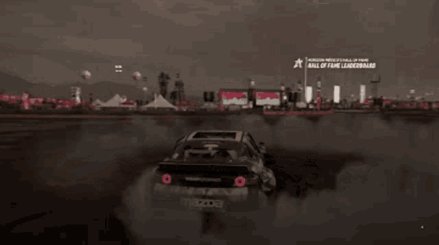 a mazda car is drifting on a track in front of a sign that says hall of fame