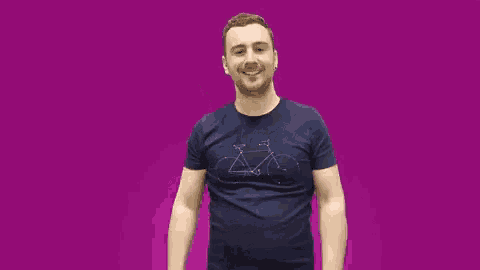 a man in a blue shirt is dancing in front of a pink background .