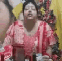 a woman in a red dress is sitting at a table with a bottle of coca cola in front of her .