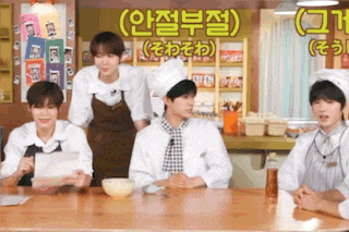 a group of young men are sitting at a table wearing chef hats .
